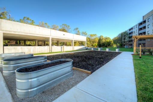 a grassy area with metal planters and benches and a building in the background