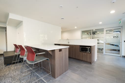 resident lounge white countertops and a wooden island with three red chairs