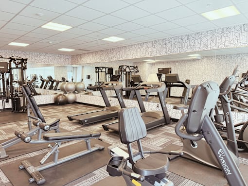 A gym with a variety of equipment including treadmills, weights, and exercise machines.