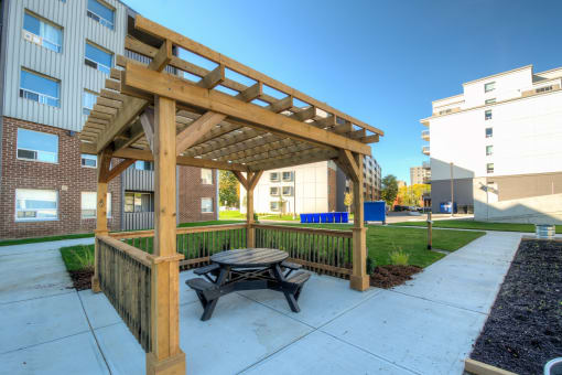 a picnic table under an awning in the courtyard of an apartment complex