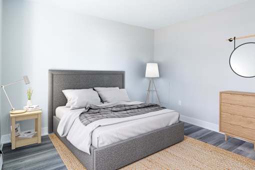 A bedroom with a large bed and a lamp on a side table.