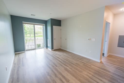 an empty living room with a sliding glass door leading to a balcony