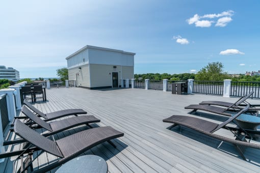 a large roof deck with lounge chairs and a hot tub