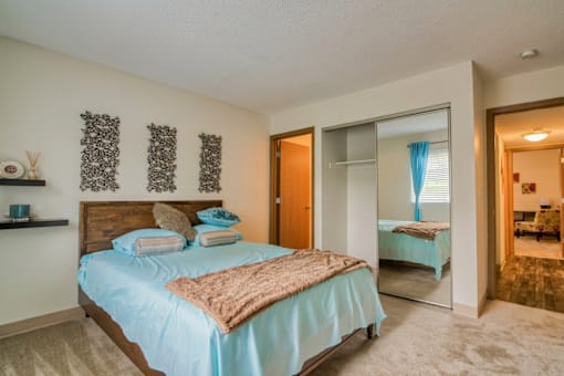 A bedroom with a bed, a mirror, and a nightstand.