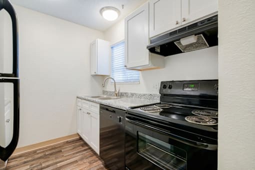 A kitchen with a black stove top oven and white cabinets.