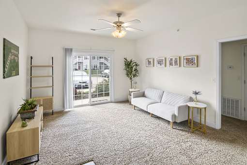a living room with a couch and a ceiling fan    and a door