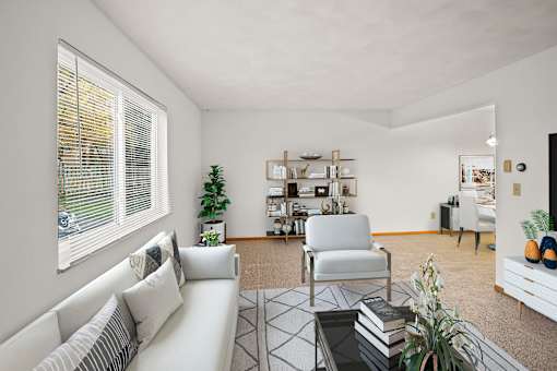 A living room with a white sofa, a chair, a coffee table, and a bookshelf.