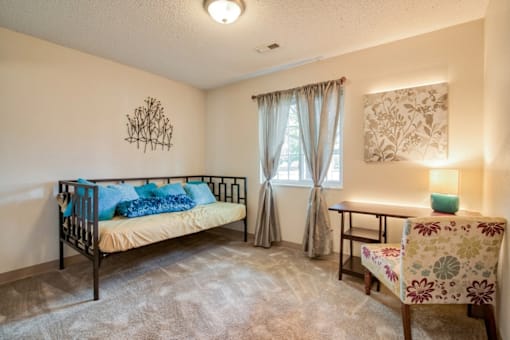 A bedroom with a bed, chair, and a wall hanging.