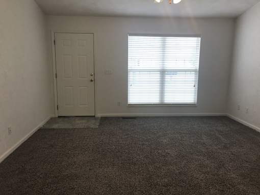A room with a door and a window with blinds.