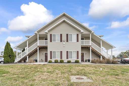 the front of a house with a porch and a lawn