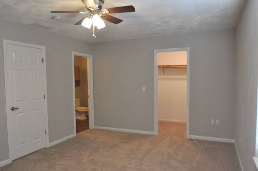 A room with a ceiling fan and carpeted floor.