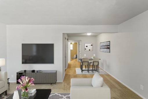 a living room with a large tv on the wall and a dining room table in the background