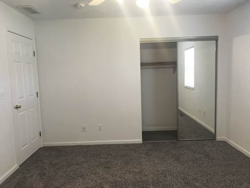 A room with a white door and a grey carpet.