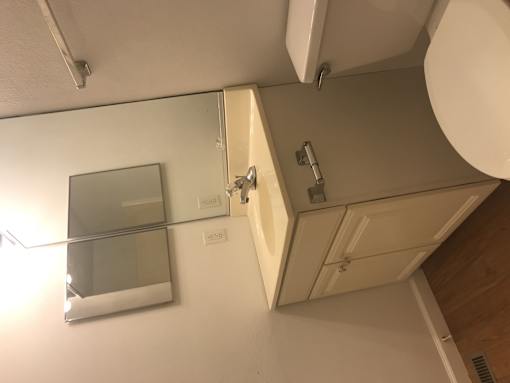 A bathroom with a toilet, sink, and mirror.