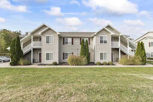 a large apartment building with a lawn and a parking lot