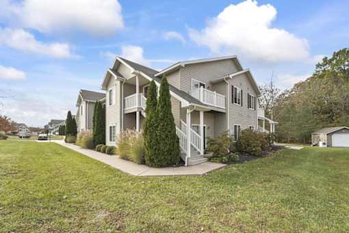 a gray house with a sidewalk in front of a grass field