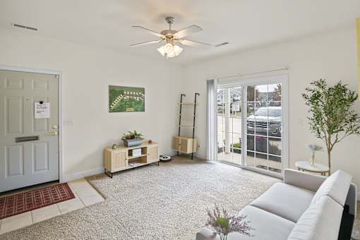 a living room with a white couch and a ceiling fan
