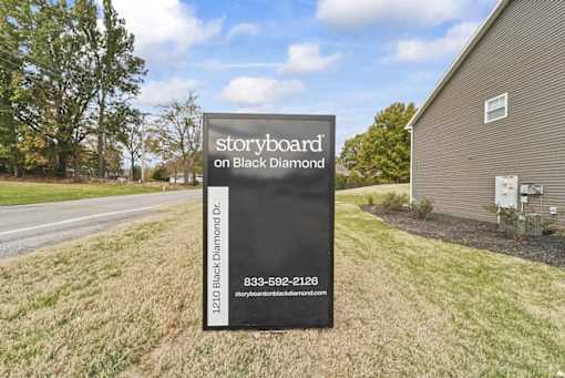 a sign on the side of a road in front of a house