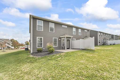 a gray house with a yard and a white fence