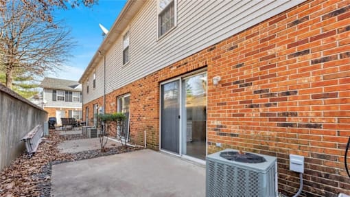 A brick wall with a sliding glass door and a wall-mounted air conditioning unit.