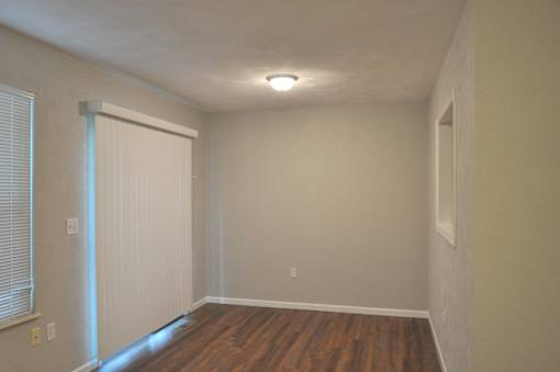 A room with a white door and wooden floor.