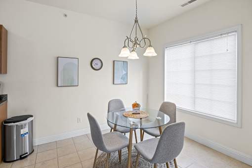 a dining room with a glass table and chairs and a large window