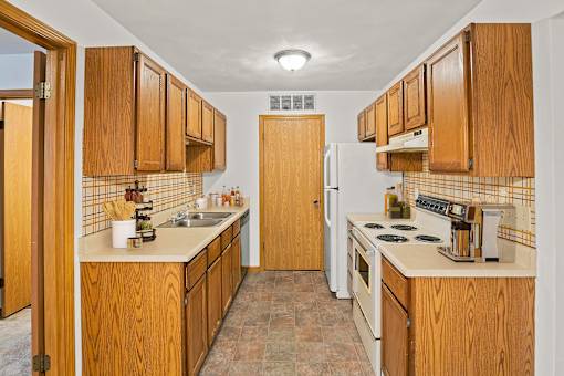 A kitchen with wooden cabinets and a white refrigerator.