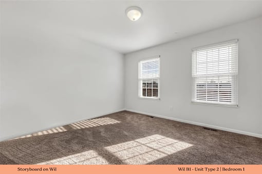 A room with a carpeted floor and two windows.