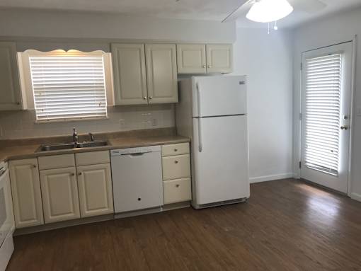 A kitchen with white appliances and wooden floors.