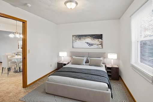 A bedroom with a large bed and a painting on the wall.