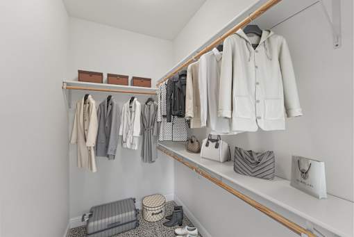 a walk in closet with shelves and racks of clothes and bags