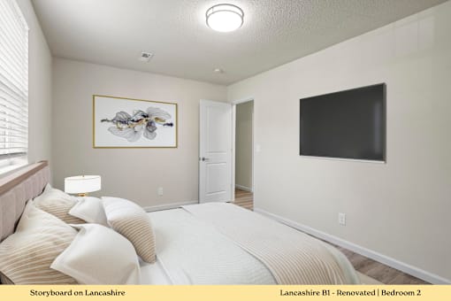 A bedroom with a bed, a painting, and a flat screen TV.