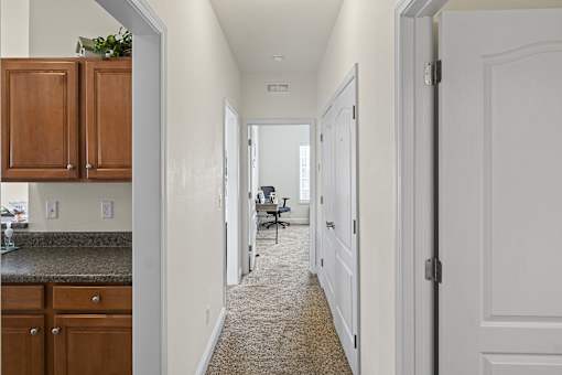 an empty kitchen with a hallway to a living room and a dining room