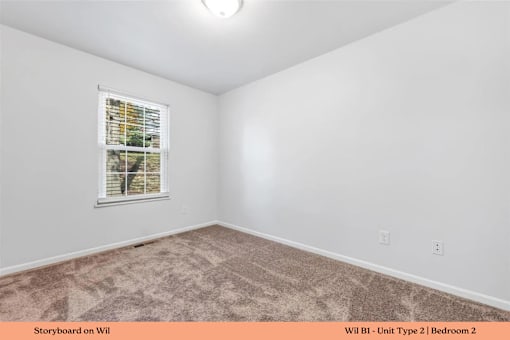 A bedroom with a carpeted floor and a window with blinds.