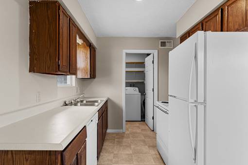 A kitchen with white appliances and brown cabinets.