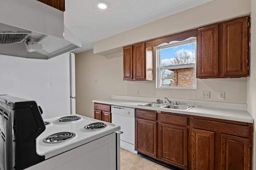 A kitchen with a white stove and brown cabinets.