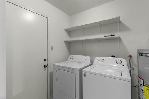 A white door is open to a laundry room with two washing machines.