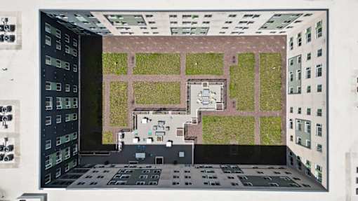 A model of a building with a green roof and a courtyard.