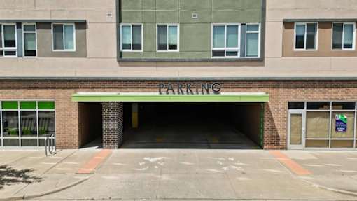 A parking garage entrance with a green sign above it.