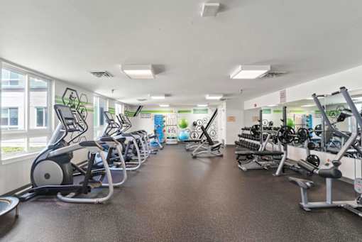 A gym with a variety of exercise equipment including treadmills, stationary bikes, and weight machines.