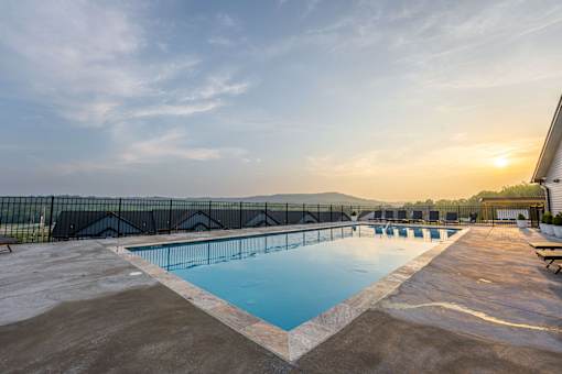 A large outdoor swimming pool with a sunset in the background.