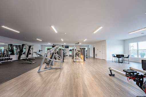 A spacious gym with a variety of equipment and a dining table.
