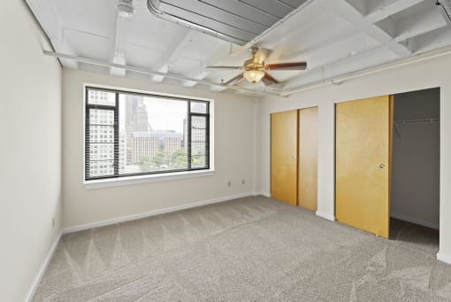 an empty room with a large window and a ceiling fan
