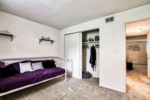 A bedroom with a purple bed and a white door.
