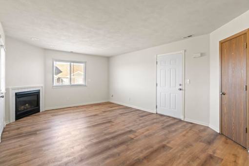 A room with a fireplace and wood flooring.