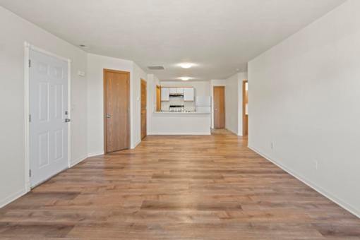 A long hallway with wooden floors and white walls.