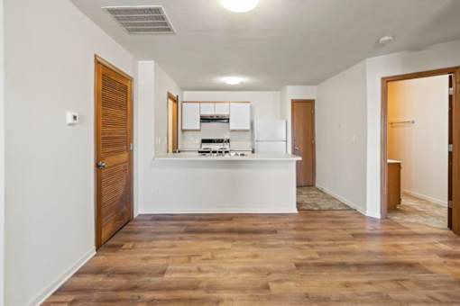 A kitchen with white appliances and wooden floors.