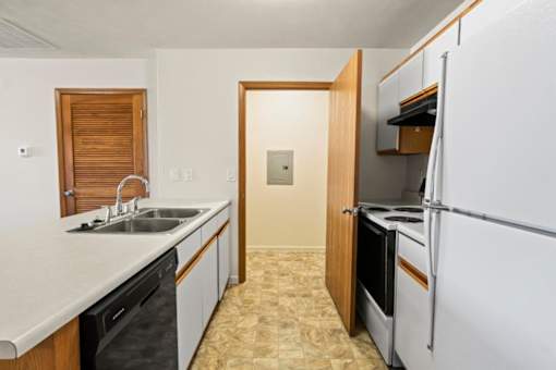 A kitchen with a sink, dishwasher, and refrigerator.