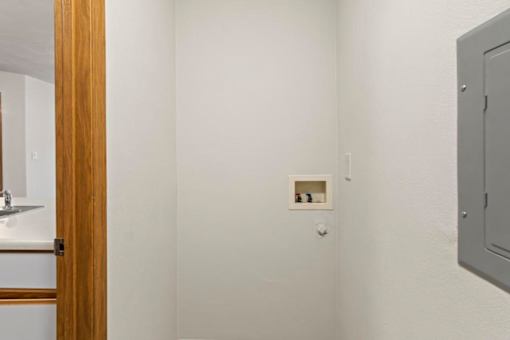 A white wall with a small picture frame and a grey electrical box.