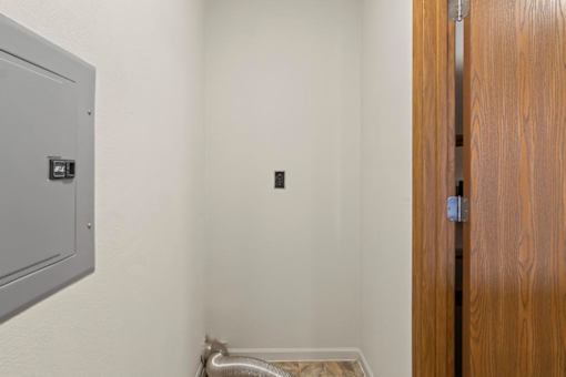 A room with a wooden door and a metal vent on the wall.